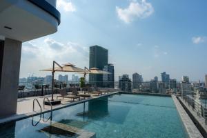 a swimming pool with chairs and umbrellas on a building at Champs Elysees Hotel & Suites in Phnom Penh