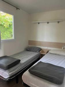 two beds in a room with a window at ZEcamping 2 étoiles animaux acceptés dans un environnement calme et naturel in Angicourt
