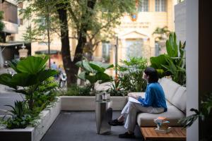 a woman sitting on a couch in a garden at MEANDER Saigon in Ho Chi Minh City