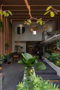 a lobby with chairs and tables and plants at MEANDER Saigon in Ho Chi Minh City