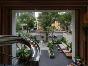 an escalator in a building with people sitting on benches at MEANDER Saigon in Ho Chi Minh City