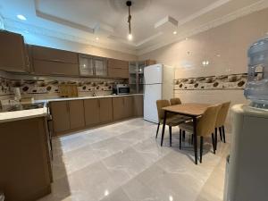 a kitchen with a table and a white refrigerator at نزل العقيق بحي الجامعة in Medina