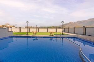 a swimming pool with two tables and mountains in the background at Hill Berry - A SoVo Hotel in Lonavala