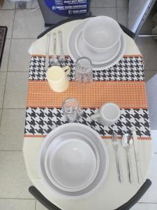 a table with white plates and utensils on it at Caishen Apartelle The Couples Getaway in Silang