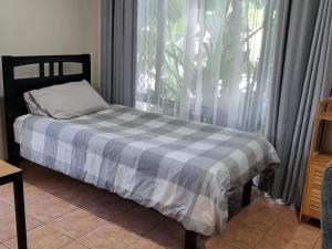 a bed with a checkered blanket in front of a window at Theme Park Getaway in Gold Coast