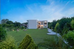 a building in the middle of a grassy yard at Corbett The Regnum Resort in Rāmnagar