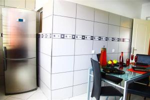 eine Küche mit einem Kühlschrank aus Edelstahl und einem Tisch in der Unterkunft Fernandes Apartment in Carvoeiro