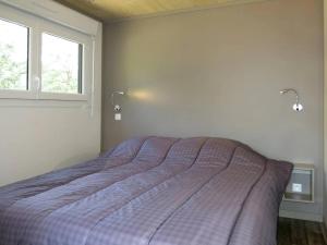 a bedroom with a bed with a purple comforter and a window at ZEcamping 3 étoiles animaux acceptés piscine et restaurant in Pluherlin
