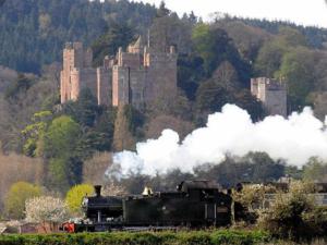 a steam train with a castle in the background at Stable Lodge in Williton