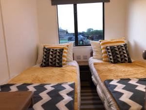 two beds in a room with a window at Stable Lodge in Williton