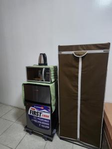 a microwave sitting on top of a box next to a refrigerator at Caishen Apartelle The Traveler Accomodation in Biga