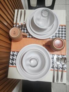 a table with white plates and utensils on it at Caishen Apartelle The Traveler Accomodation in Biga