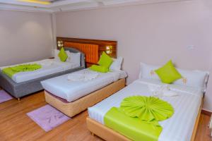 a room with two beds with green pillows at Arise Sunshine Hotel in Narok