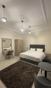 ein Schlafzimmer mit einem Bett, einem Schreibtisch und einem Spiegel in der Unterkunft شقق نسائم ورد in Ta'if