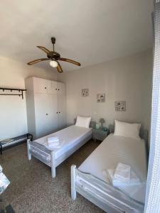 two beds in a room with a ceiling fan at Studio Mytzela in Amaliapoli