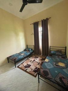 two beds sitting in a room with a window at Ramly Homestay in Kuala Terengganu