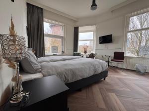 a bedroom with a bed and a table and two windows at Stad & Strandhotel Elisabeth in Vlissingen