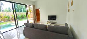 a living room with a couch and a television at Samma Villas - Agate Villa - 1 BDR & private pool in Ko Phangan