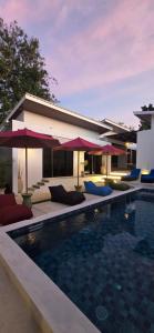 a swimming pool with chairs and umbrellas next to a house at Stars Villa in Ngingas