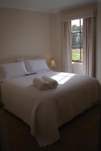 a bedroom with a white bed with towels on it at Buttons Cottage for a northwest Tassie escape in Nietta