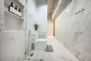 a white bathroom with a toilet and a shower at Swing By in Bangkok +70 photos