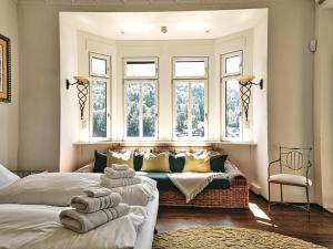 a bedroom with two beds and a couch and windows at Rottenhöfer Retreat Villa in Berchtesgaden