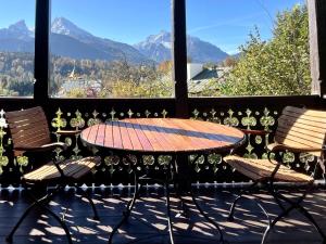 a table and chairs on a balcony with mountains at Rottenhöfer Retreat Villa in Berchtesgaden