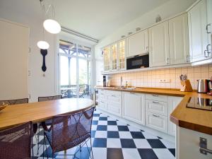 a kitchen with white cabinets and a checkered floor at Rottenhöfer Retreat Villa in Berchtesgaden +17 photos