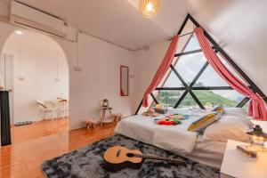 a bedroom with a large window and a bed with a guitar at Mon Mon Homestay in Mon Jam