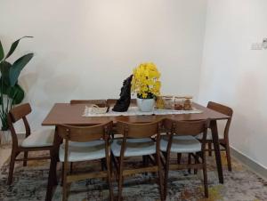 a dining room table with chairs and a vase of flowers at Seri Jerantut Homestay in Jerantut