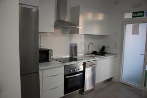 a kitchen with white cabinets and a stove top oven at Apartamentos Lumael in Mérida