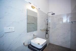 a white bathroom with a sink and a mirror at Palms shede Villa in Habaraduwa Central +48 photos
