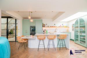 a kitchen with a island with bar stools at Chic Devon Designer Oasis with hot tub in Malborough