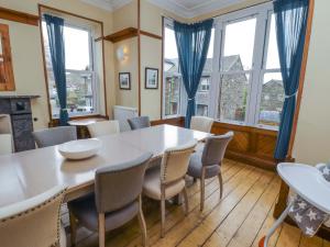 a dining room with a table and chairs and windows at 1 Park Road in Windermere