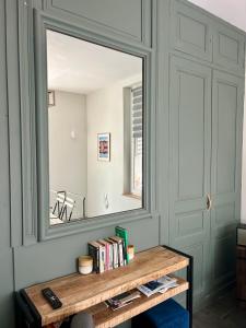 a mirror on a wall above a table with books at L'Escale à Villerville in Villerville