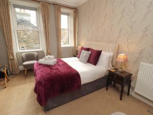 a bedroom with a large bed with a purple blanket at 1 Park Road in Windermere