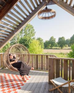 a woman sitting in a wicker swing on a deck at Le jardin des 4 saisons in Le Mans