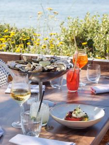 a table with a plate of food and glasses of wine at Logis Hôtel Les Mouettes Restaurant ERIN - Larmor Plage, Proche de LORIENT in Larmor-Plage