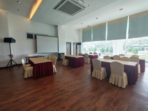 a conference room with tables and chairs and a screen at Kingston Hotel 18 - Kuala Lumpur Sri Damansara in Kuala Lumpur