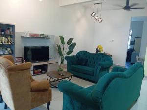 a living room with two blue chairs and a tv at Seri Jerantut Homestay in Jerantut +9 photos