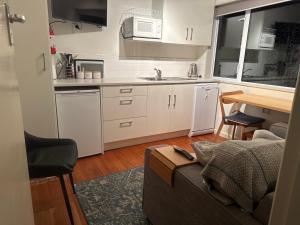 a small kitchen with white cabinets and a couch at Redcliffs On Park By Sea in Christchurch
