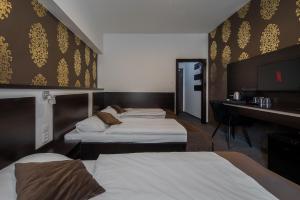 a hotel room with three beds and a desk at Hotel Polo in Prešov