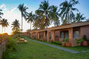 a row of houses with palm trees in the background at Los Londos Batukaras in Cijulang Nusawiru Airport