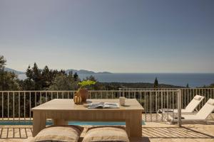 a wooden table and two white chairs on a balcony at Magganos Sunset Villas in Fiskardo