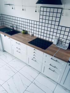 a kitchen with white cabinets and black tiles at 3 pièces TERRASSE et JACUZZI in Nîmes