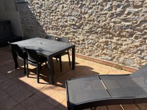 a black table and chairs in front of a stone wall at 3 pièces TERRASSE et JACUZZI in Nîmes +4 photos