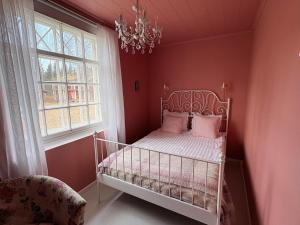 a bedroom with a bed with pink walls and a chandelier at Wiisalan Kartano in Savonlinna