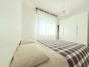 a bedroom with a bed with a plaid blanket at S357 - Sirolo, luminoso trilocale con posto auto in Sirolo
