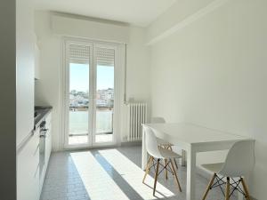 a white dining room with a white table and chairs at S357 - Sirolo, luminoso trilocale con posto auto in Sirolo