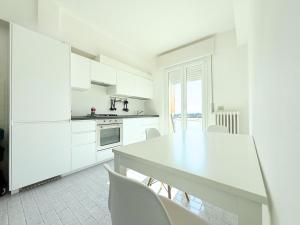a kitchen with white cabinets and a table and chairs at S357 - Sirolo, luminoso trilocale con posto auto in Sirolo